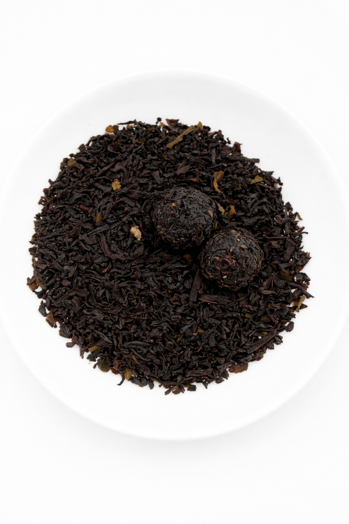 Black tea leaves in a white bowl on a white background