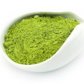 Green powder in a white bowl on a white background