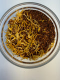 Glass jar with yellow and brown dried herbs on a white background